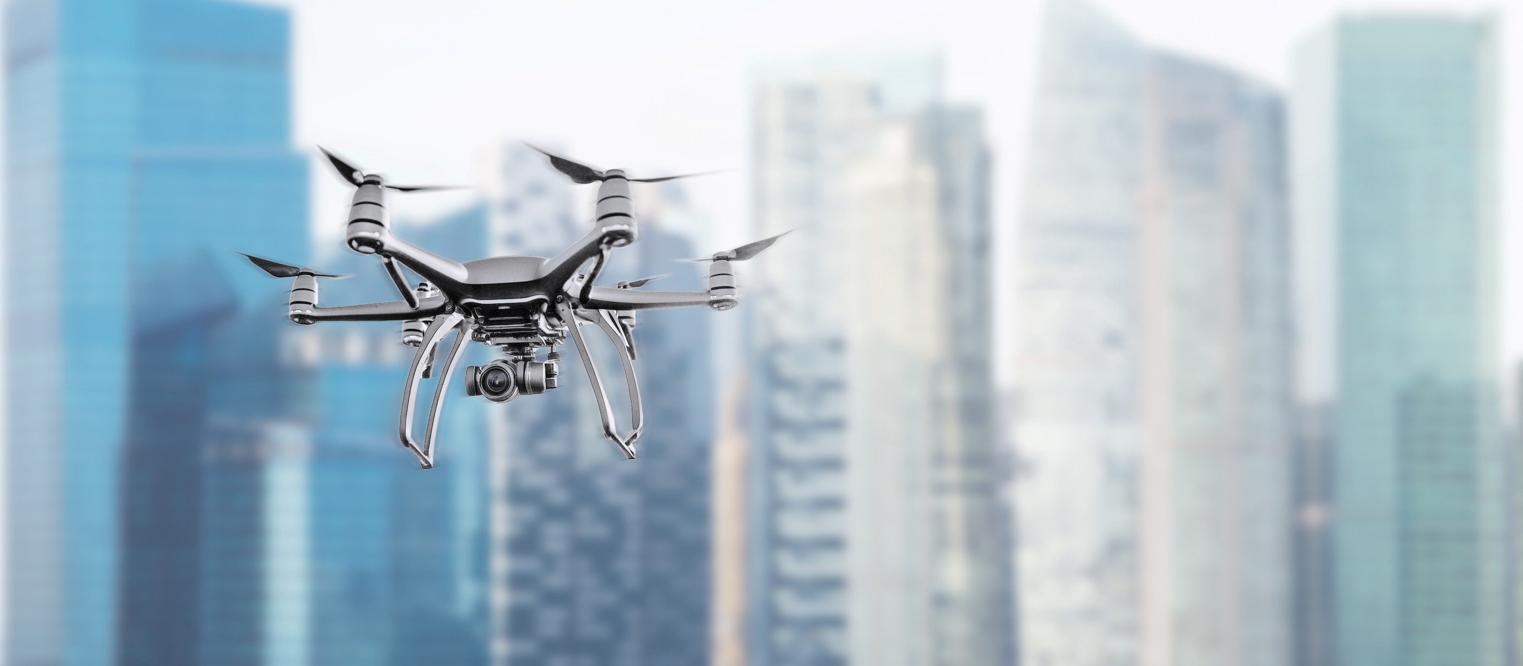 : Multirotor drone with camera flying in front of a high-rise urban skyline 